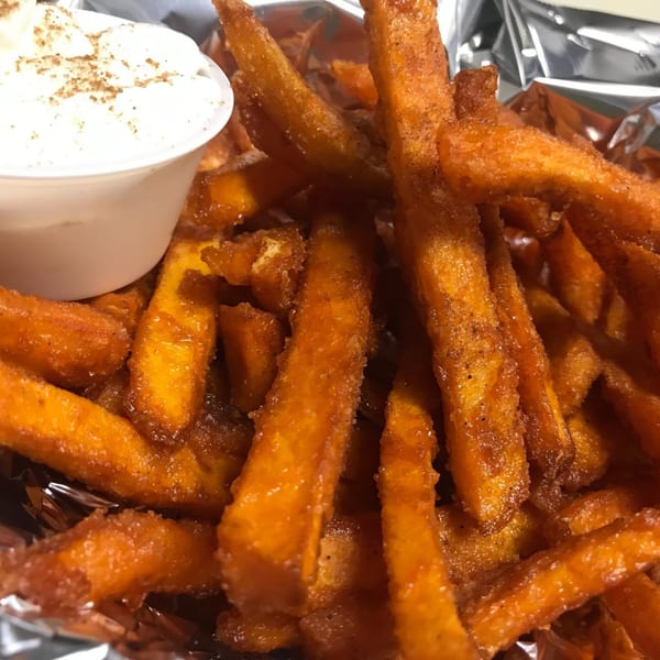 Close-up of Abby Lane's sweet potato fries with cinnamon sugar and a side of dipping sauce.