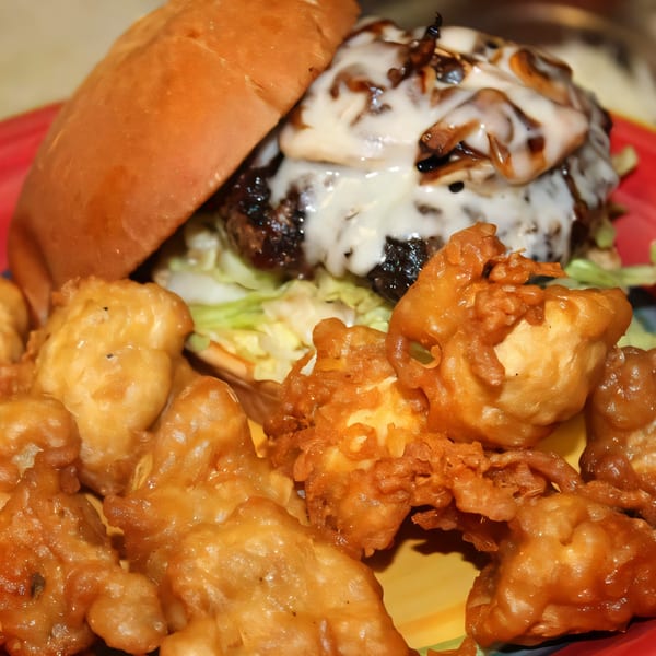 Abby Lane Gourmet Burger with melted cheese and caramelized onions, served with crispy fried cauliflower.